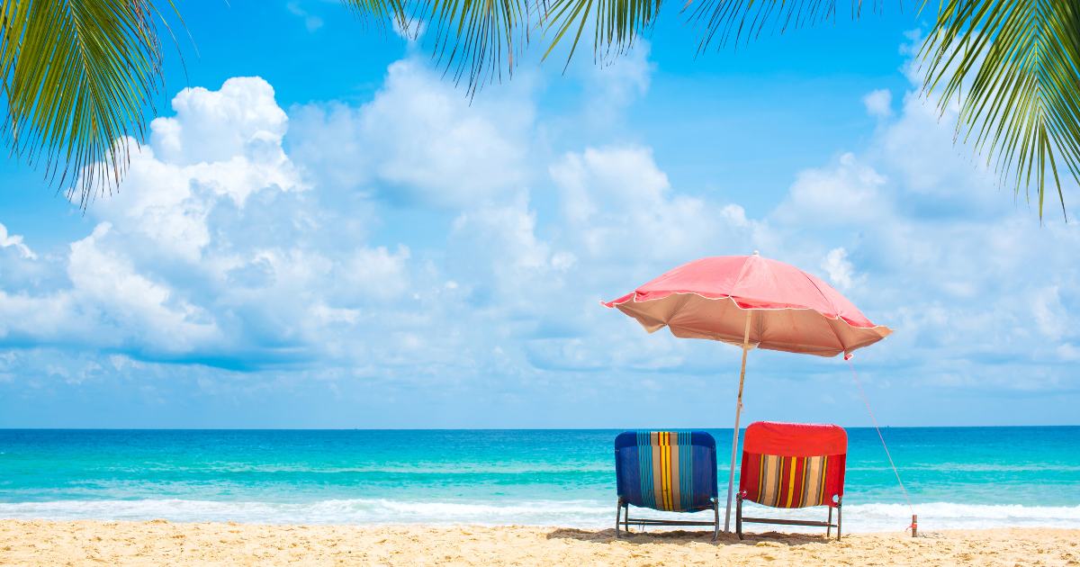 A beautiful view of a beach with two chairs and an umbrella