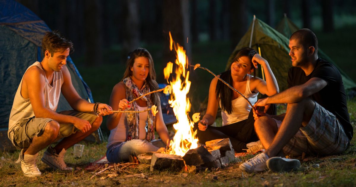 A group of people roasting s'mores around a campfire